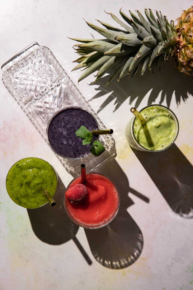 Smoothies in glasses with a pineapple on subtle pastel backdrop