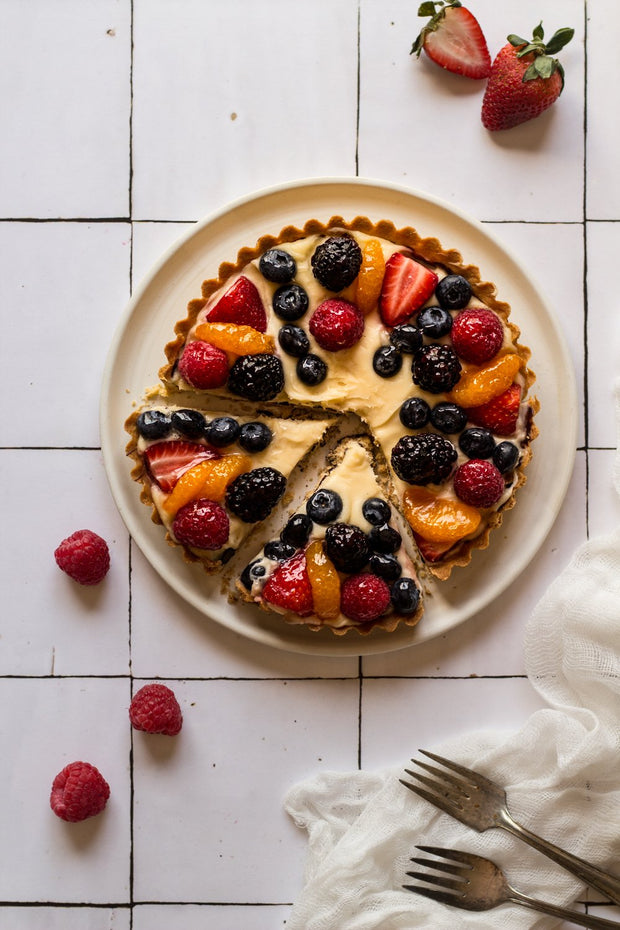 Sliced berry fruit tart up with forks and linen on a Moroccan Tile Replica Photography Backdrop 