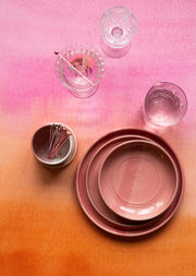 Pink and orange ombre backdrop with pottery and glasses